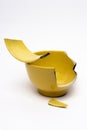 Vertical shot of a broken yellow bowl, one of the broken particles placed on top of the bowl