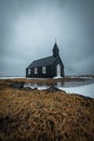 Vertical shot of Budakirkja church and its reflection in the water in front in Budir, Iceland