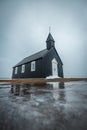 Vertical shot of Budakirkja church and its reflection in the water in front in Budir, Iceland