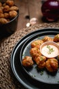 Vertical shot of Buffalo cauliflower bites served on a black plate with a sauce at a restaurant Royalty Free Stock Photo