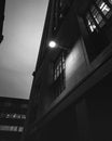 Vertical shot of a building facade with a lit street lamp in grayscale Royalty Free Stock Photo