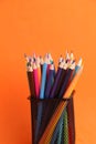 Vertical shot of a bunch of colorful pencils on metal holder isolated on orange background Royalty Free Stock Photo