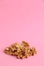 Vertical shot of a bunch of walnuts on a pink background