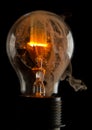 Vertical shot of a burning light bulb with smoke coming out of it isolated on a black background Royalty Free Stock Photo