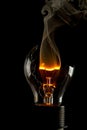 Vertical shot of a burning light bulb with smoke coming out of it isolated on a black background Royalty Free Stock Photo