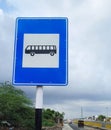 Vertical shot of the bus stop sign in a blue and white circle on a pole against a cloudy sky Royalty Free Stock Photo