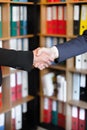 Vertical shot of businessmen shaking hands after having an agreement with binder in the background Royalty Free Stock Photo