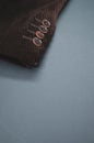 Vertical shot of the buttons of the sleeve of a brown corduroy jacket placed on a gray surface