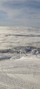 Vertical shot of a cableway on the snowy mountainside above the clouds on a sunny day