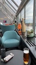 Vertical shot of a cafe table with a glass of beer and blue armchairs