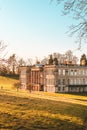 Vertical shot of Calke Abbey in a green grass field on a sunny day, United Kingdom