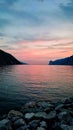 Vertical shot of a calm pink sunset over the rocky sea shore Royalty Free Stock Photo