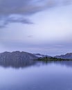 Vertical shot of a calm reflective lake on a mountain range background