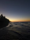 Vertical shot of a calm sunset over the sea with silhouette of trees at the shore Royalty Free Stock Photo