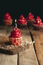 Vertical shot of a candle cupcake with red cream Royalty Free Stock Photo