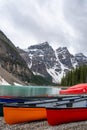 Vertical shot of canoes on the shore of Moraine Lake surrounded by snowy hills in Canada Royalty Free Stock Photo
