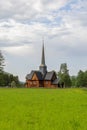 Kvikne kirke\'s towering spire rises in greenery, blending history with pastoral charm