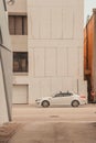 Vertical shot of a car parking in front of a white building with some cracks