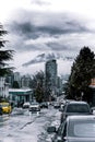 Vertical shot of cars on a street surrounded by trees and buildings under a cloudy sky Royalty Free Stock Photo