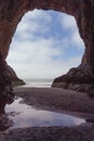 Vertical shot of a carved cave window by the water