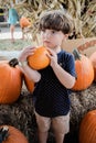 Vertical shot of a caucasian little boy holding a pumpkin at a patch Royalty Free Stock Photo