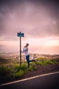 Vertical shot of a Caucasian male posing near the signpost on Camino Las Hoyas road, Tenerife, Spain