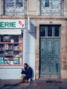 Vertical shot of a Caucasian man squatted on the street against a building in Nantes, France