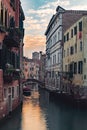 Vertical shot of a channel surrounded by buildings of Venice in Italy at sunset