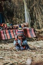 Vertical shot of child sitting on dry bamboo plants of Uros Island, Peru.