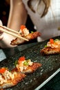 Vertical shot of chopsticks picking up a gourmet crispy rice salmon sushi roll