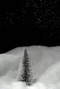 Vertical shot of a Christmas tree shining in pouring snowflakes