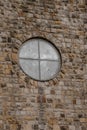 Vertical shot of circle glass window in stones wall of old medieval church Royalty Free Stock Photo