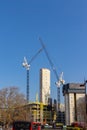 Vertical shot of a city view with two tall construction cranes working in progress