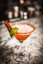 Vertical shot of a classic margarita cocktail with a slice of lime and salty rim on bar counter Royalty Free Stock Photo