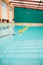 Vertical shot of a clean indoor gym pool full of water under sunlight with bulkheads dividing lanes Royalty Free Stock Photo