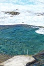 Vertical shot of a clear seawater pool next to a wavy ocean Royalty Free Stock Photo