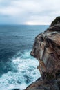 Vertical shot of a cliff and the blue sea on a cloudy day Royalty Free Stock Photo