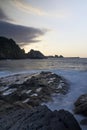 Vertical shot of a cliff at a rocky beach at sunset Royalty Free Stock Photo