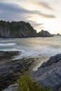 Vertical shot of a cliff at a rocky beach at sunset Royalty Free Stock Photo