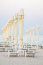 Vertical shot of closed beach umbrellas and rows of chairs on a shore