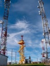Vertical shot of a cloudy sky behind telecommunication wireless towers with antennas