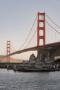 Vertical shot of the coast guard boats crossing under the Golden Gate Bridge at sunset