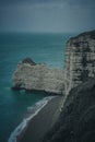 Vertical shot of coastal cliffs against sea waves on a cloudy day Royalty Free Stock Photo