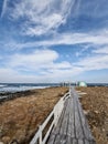 Vertical shot of a coastal path leading to a `Water Sports` sign and the blue sea on a cloudy day Royalty Free Stock Photo