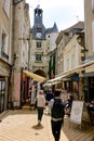 Vertical shot of a cobblestone alley with shops in Amboise full of people and magnificent buildings