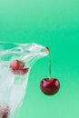 Vertical shot cold water with ice in the glass and pair of fresh cherries.