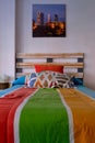Vertical shot of a colorful bed in the room with a picture of skyscrapers hanging on the wall