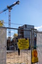 Vertical shot of the construction site through a construction fence with a warning sign on it
