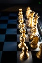 Vertical shot of cool gold chess pieces in the starting position reflected on the board