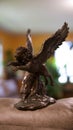 Vertical shot of a copper figure of a winged lion on a leather sofa indoors
